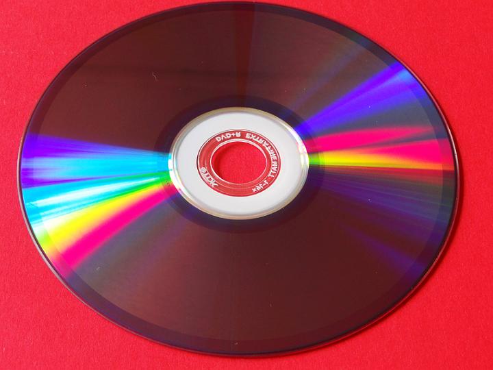 AK02.jpg - Een CD of in dit geval een DVD blijft onder de juiste hoek van lichtval een fascinerend object. Ik denk alleen dat een veel donkerder ondergrond het schijfje nog beter had laten uitkomen.