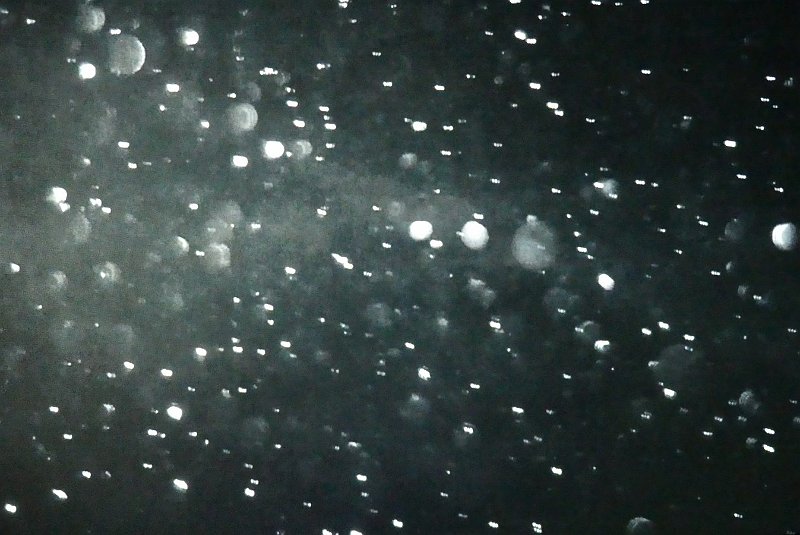 AJ01.JPG - Het licht weerkaatst zo te zien op vallende sneeuwvlokken. Hoe dichter bij de camera ze vallen hoe onscherper en ronder ze worden.